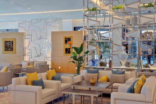 迪拜Hilton Dubai Palm Jumeirah的大堂设有白色的沙发以及黄色和蓝色的枕头。