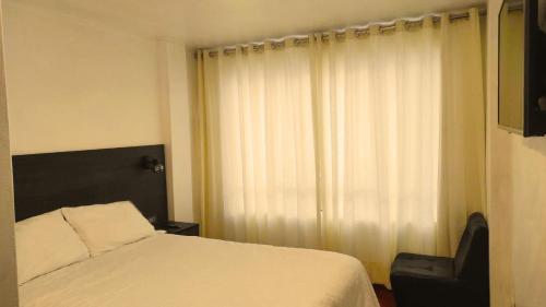 安达韦拉斯Apartamento Andahuaylas的卧室配有一张床和一把椅子,靠窗