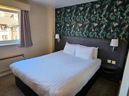 曼彻斯特钟摆酒店 的一间卧室设有一张带花卉墙壁的大床