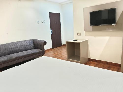 勒克瑙Hotel Sharma Regency的客房设有床、沙发和电视。