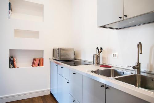 米兰Vittore Rooms & Apartment的厨房配有白色橱柜和水槽