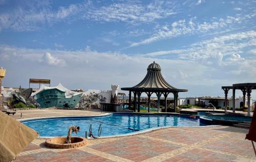 达哈布Black Prince Hotel的一座游泳池,毗邻一座建筑,设有凉亭