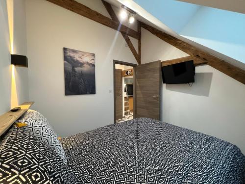 比桑Gîte Au Creux Du Moulin的一间卧室配有一张床和一台平面电视
