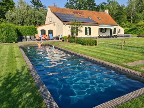 伊普尔Cottage de Vinck的一座带房子的院子内的游泳池