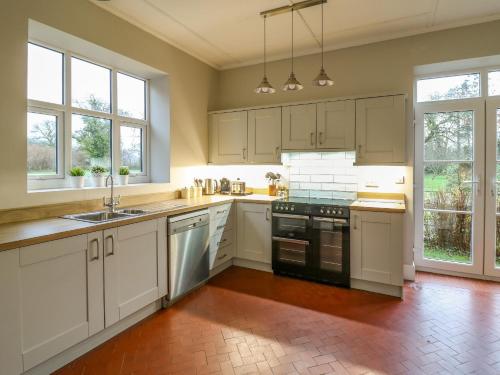 LlanwrdaTirallen的厨房配有白色橱柜、电器和窗户