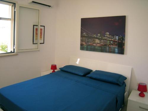 托雷瓦多Villa Giulia Salento Mare的卧室配有蓝色的床和墙上的绘画作品
