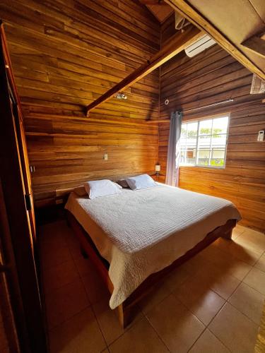 Alto BoqueteLas cabañas del Francés的木制客房内的一间卧室,配有一张床