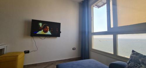 亚历山大شقة فاخرة مكيفة تري البحر مباشرة的客厅设有窗户,墙上配有电视