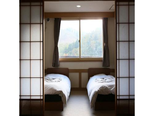 志贺高原Shiga Palace Hotel - Vacation STAY 22531v的客房设有两张床和窗户。