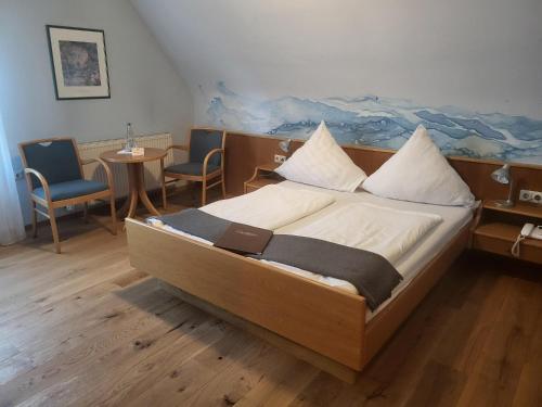 Zuzenhausen达赫森弗兰茨酿酒厂旅馆的一间卧室配有一张带两把椅子和一张桌子的床。