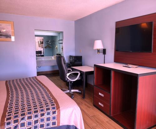 里奇兰Rodeway Inn的酒店客房配有一张床和一张书桌及一台电视