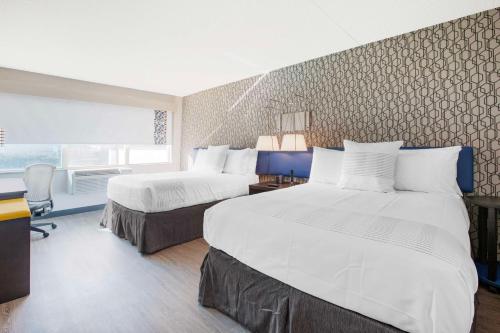 米西索加GLō Best Western Mississauga Corporate Centre的酒店客房配有两张床和一张书桌