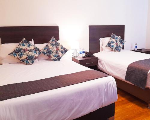阿雷基帕Hotel La Casa de Irma的配有白色床单的酒店客房内的两张床