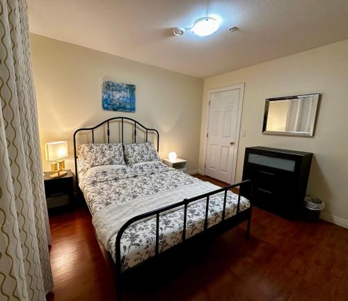 温哥华SixPine Suite的一间卧室配有一张床、两盏灯和一台电视。