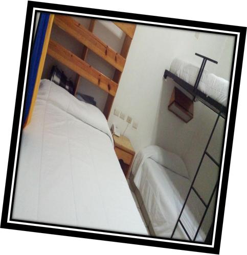 维多利亚城Hostal de Escandón的小房间设有两张床,墙上有一个十字架