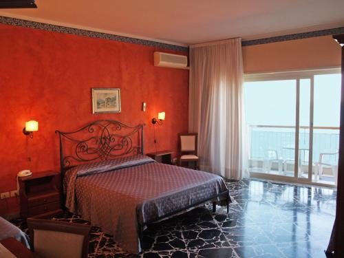 贾迪尼-纳克索斯哥斯达阿祖拉酒店的一间卧室配有一张红色墙壁的床