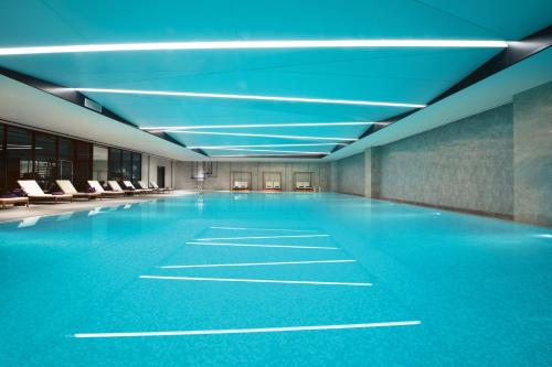 杭州杭州奥克斯中心皇冠假日酒店的一座带蓝色天花板和椅子的空游泳池