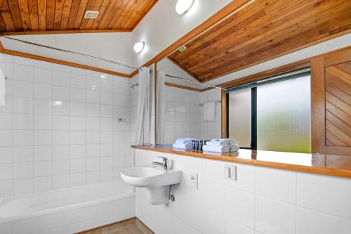 布伦海姆Riverside Hotel Marlborough的一间带水槽和浴缸的浴室以及窗户。
