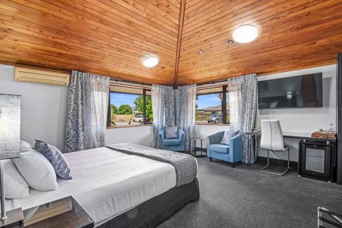 布伦海姆Riverside Hotel Marlborough的一间卧室配有一张床、两把椅子和一台电视