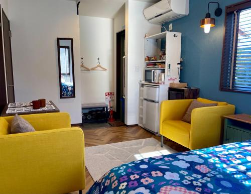常滑市Kiwi House Tokoname VACATION STAY的一间带两张黄色椅子的客厅和一间厨房