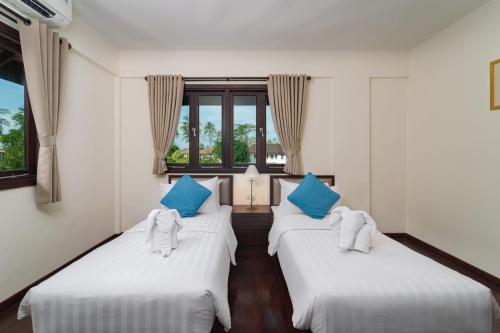 拉古洼班育波鲁别墅酒店的配有两张床铺的蓝色和白色枕头