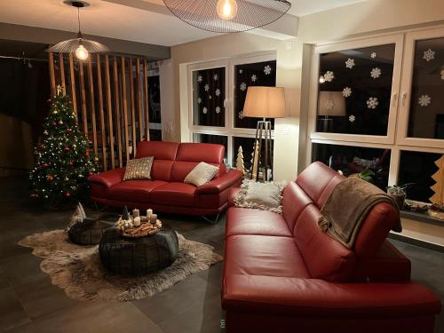 RohrwillerMaison d hotes Coeur de Village Alsace & spa的客厅配有红色的沙发和圣诞树