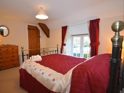 Winsham3 Bed in Lyme Regis BARRA的一间卧室配有一张带红色棉被的床和窗户。