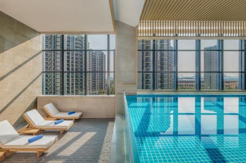 绍兴绍兴上虞万豪酒店的酒店游泳池设有椅子,享有摩天大楼的景色