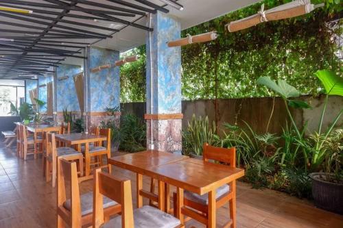 KembaranRedDoorz near Universitas Muhammadiyah Purwokerto 2的餐厅设有木桌和椅子,种有植物