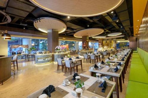 班达楠榜Golden Tulip Springhill Lampung的一间带桌椅的餐厅和一间酒吧