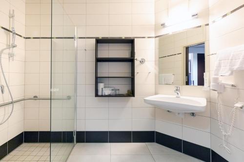 特雷芬育优酒店 的一间带水槽和玻璃淋浴的浴室