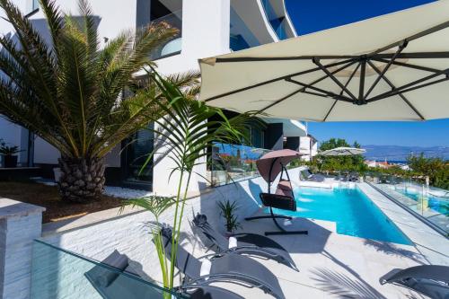 巴斯卡Villa Valis的一座带遮阳伞的游泳池位于大楼旁