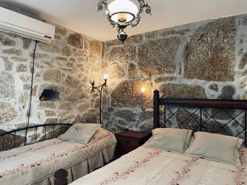 Aldeia Viçosa金塔多米奥旅馆的一间卧室设有两张床和石墙