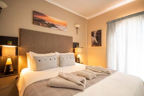比勒陀利亚Meadowbrook Guesthouse的卧室配有白色床和毛巾