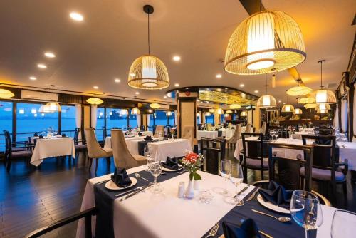 下龙湾Aquamarine Premium Cruise的餐厅配有白色的桌椅和灯光