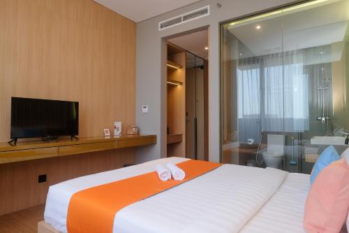 DemanganSans Hotel RG Living Jogja by RedDoorz的一间卧室设有一张带电视的床和一间浴室。