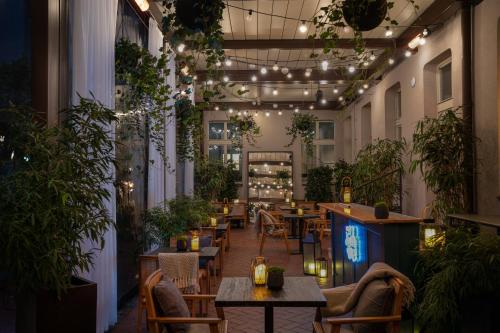 布拉格Falkensteiner Boutique Hotel Prague的一间设有桌子和盆栽植物及灯的餐厅