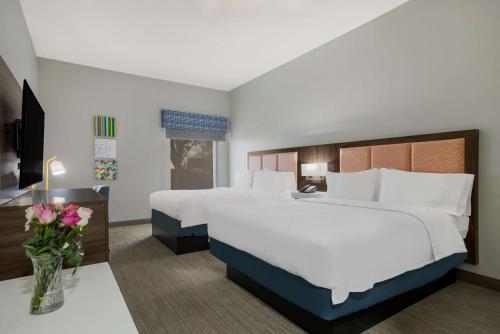 林登林登汉普顿酒店的酒店客房,设有两张床和一张鲜花桌。