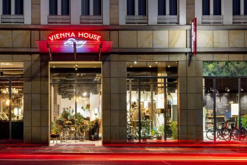 莱比锡Vienna House Easy by Wyndham Leipzig的夜间在建筑物前的商店