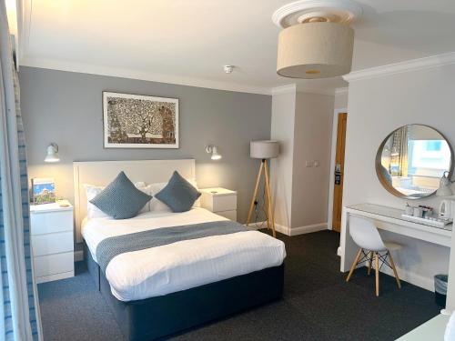 布莱顿霍夫传奇酒店的一间卧室配有一张带书桌和镜子的床