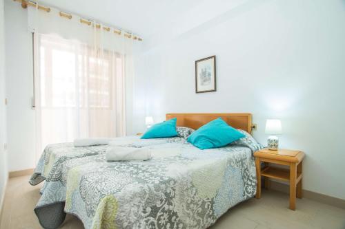 卡尔佩Apartamento Calpeplaya - PlusHolidays的一间卧室配有一张带蓝色枕头的床。