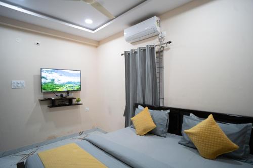 海得拉巴Yellow Bells Gachibowli的一间卧室配有一张带黄色枕头的床和一台电视。