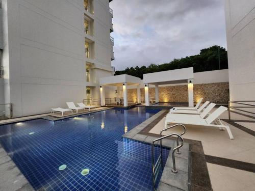 长滩岛Aloha Ocean Garden Villas Boracay的酒店游泳池设有白色椅子,酒店大楼