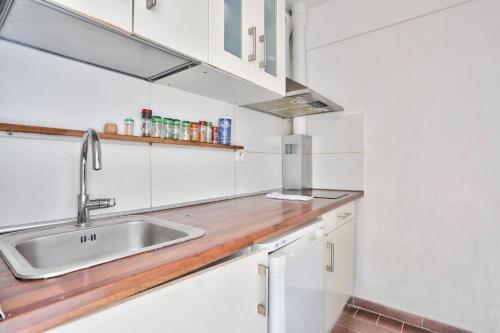 巴黎BEL APPARTEMENT PARISIEN PARC MONTSOURIS的厨房配有白色橱柜和水槽