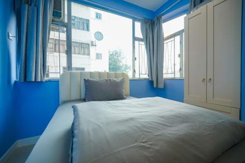香港Student Accommodation - 276 Gloucester Road的蓝色卧室设有一张带大窗户的床