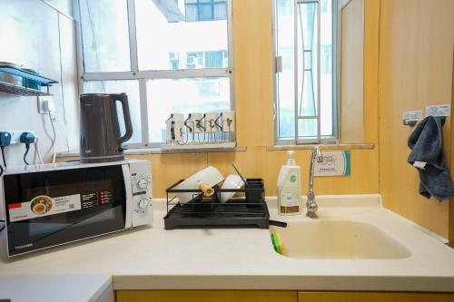 香港Student Accommodation - 276 Gloucester Road的厨房柜台配有微波炉和水槽