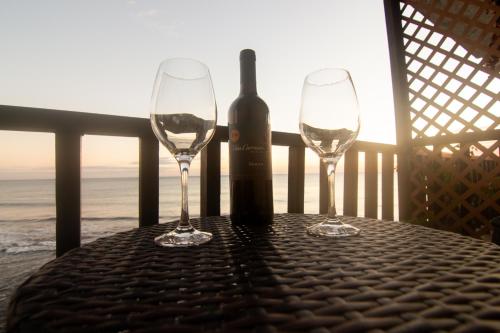 拉利伯塔德Acogedor con vista al mar的两杯酒杯坐在桌子上,并配上一瓶葡萄酒