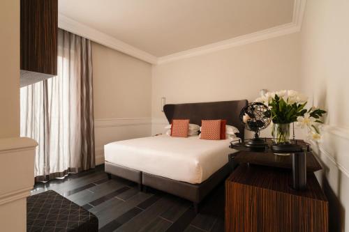 罗马纳沃纳宫酒店的一间卧室配有一张床和一张鲜花桌