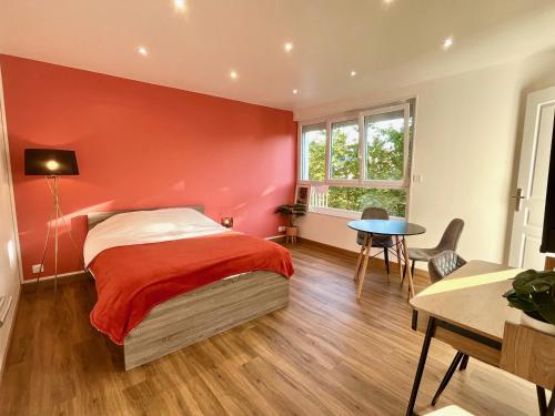 凯恩Charmant studio + parking privé的红色卧室配有床和桌子