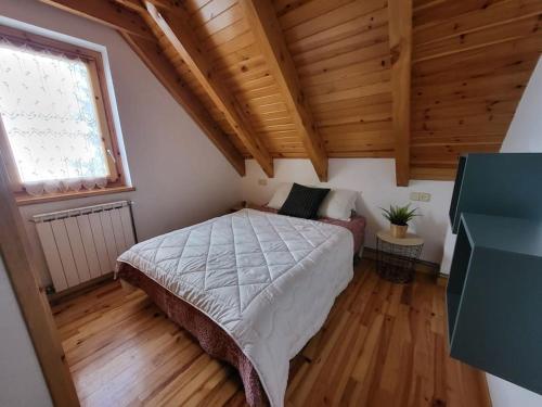 博西Duplex en la Vall de Boí, plena naturaza的一间带一张床的卧室,位于带木制天花板的房间内